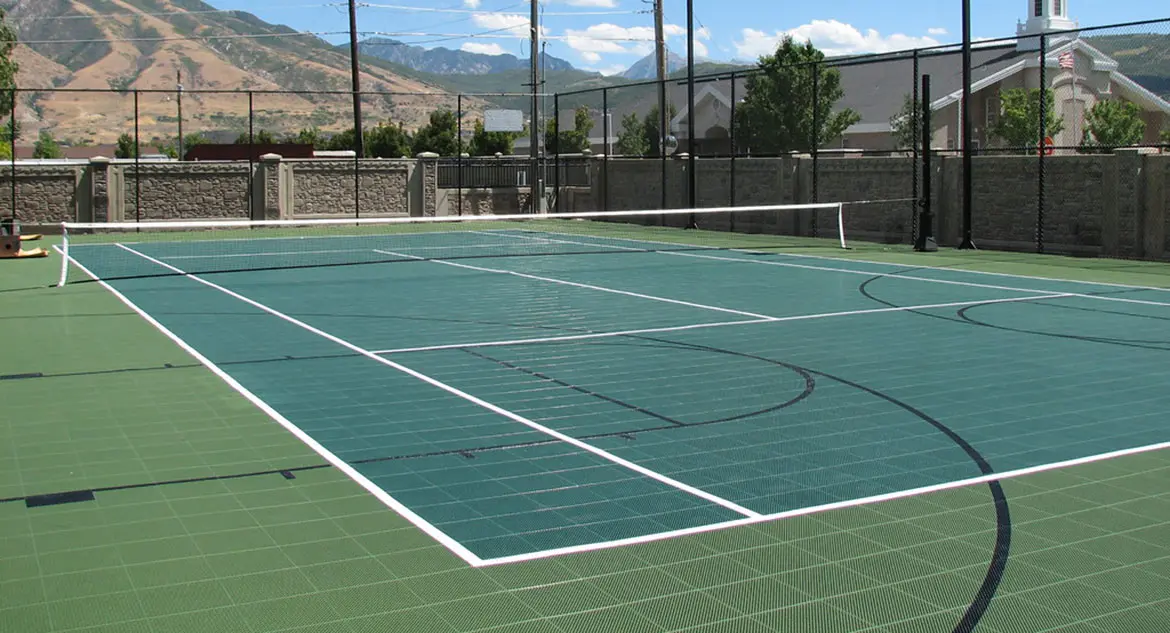 A tennis court with a net and trees in the background.