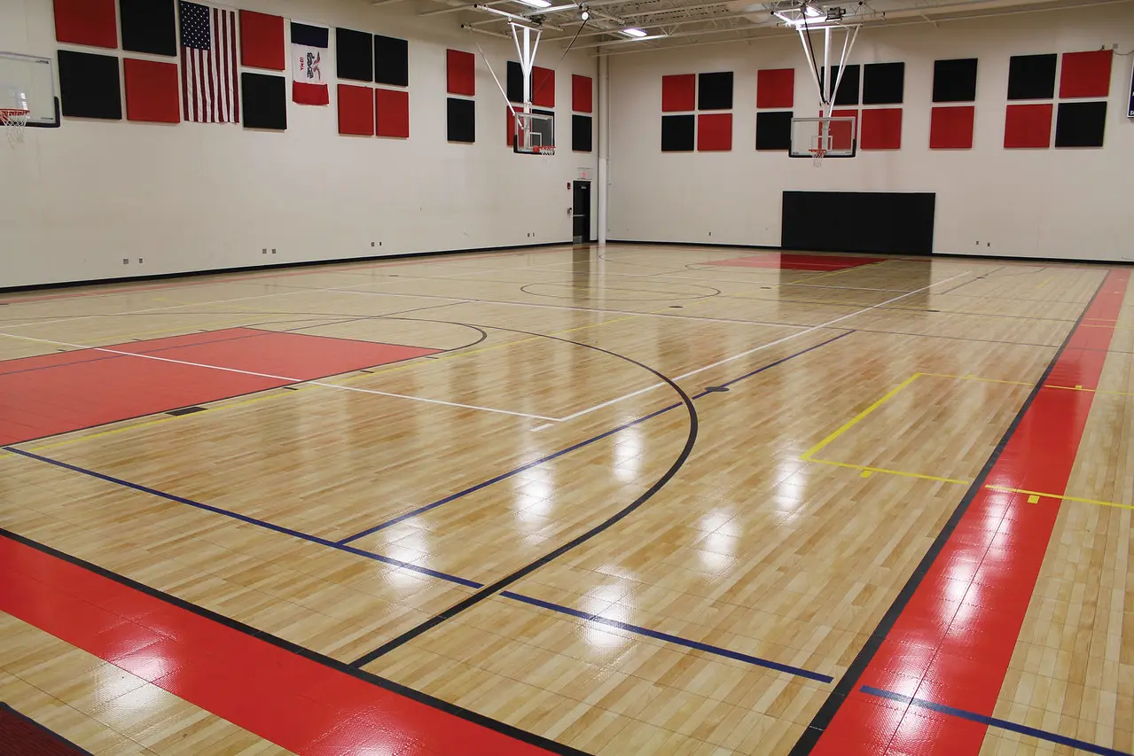 A gym with basketball court and red and white walls.