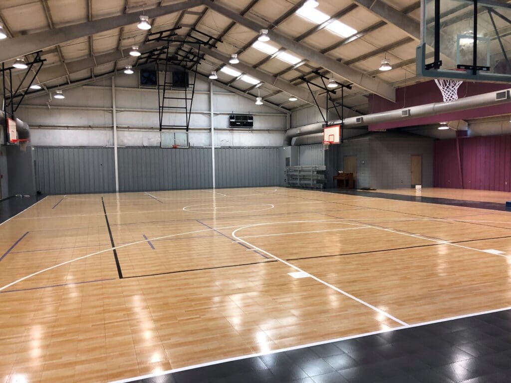 A basketball court with wooden floors and a large wall.