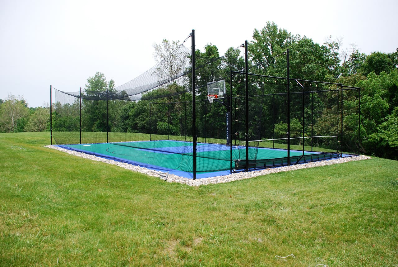 A tennis court with a net and basketball hoop.