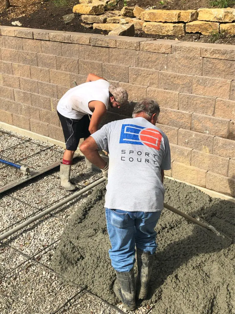 Two men working on a concrete wall.