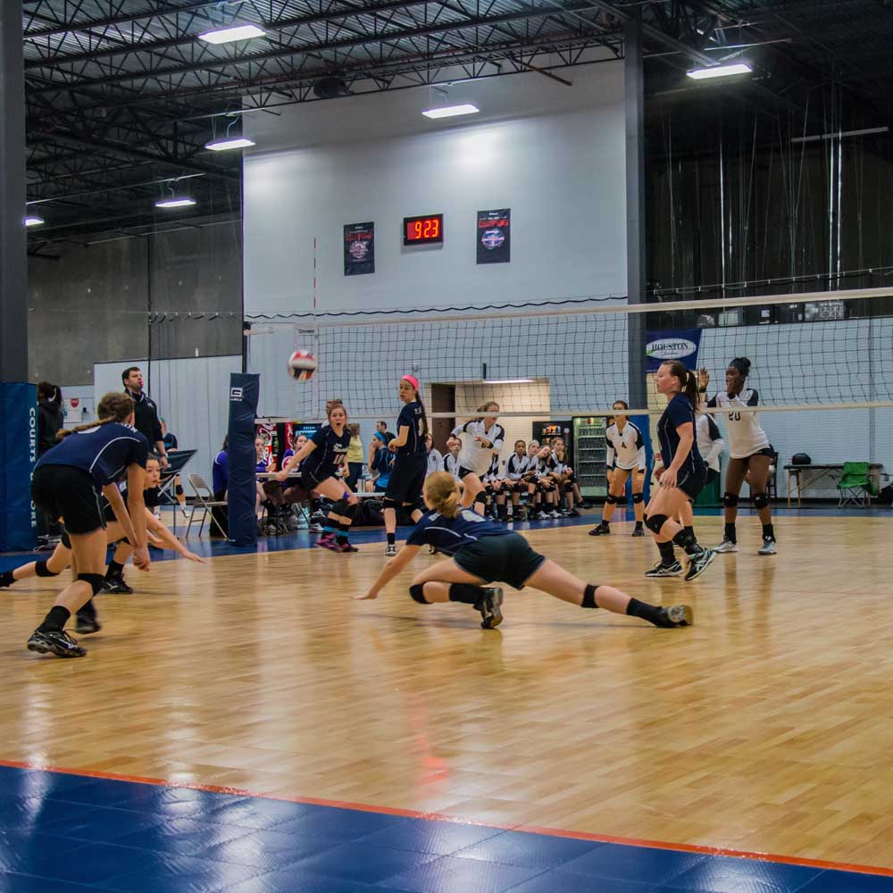 A group of people playing volleyball on the court