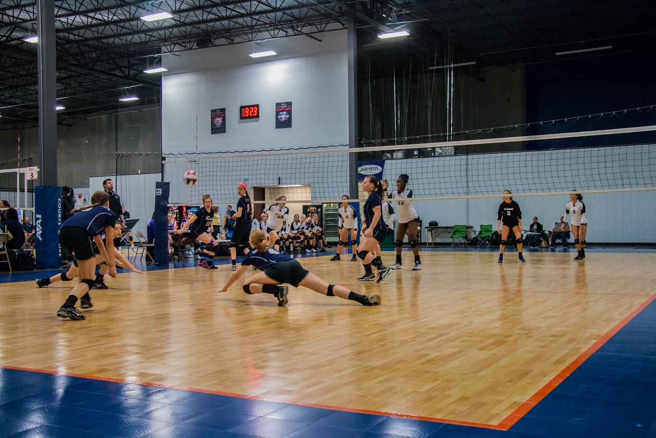 A group of people playing volleyball on the court