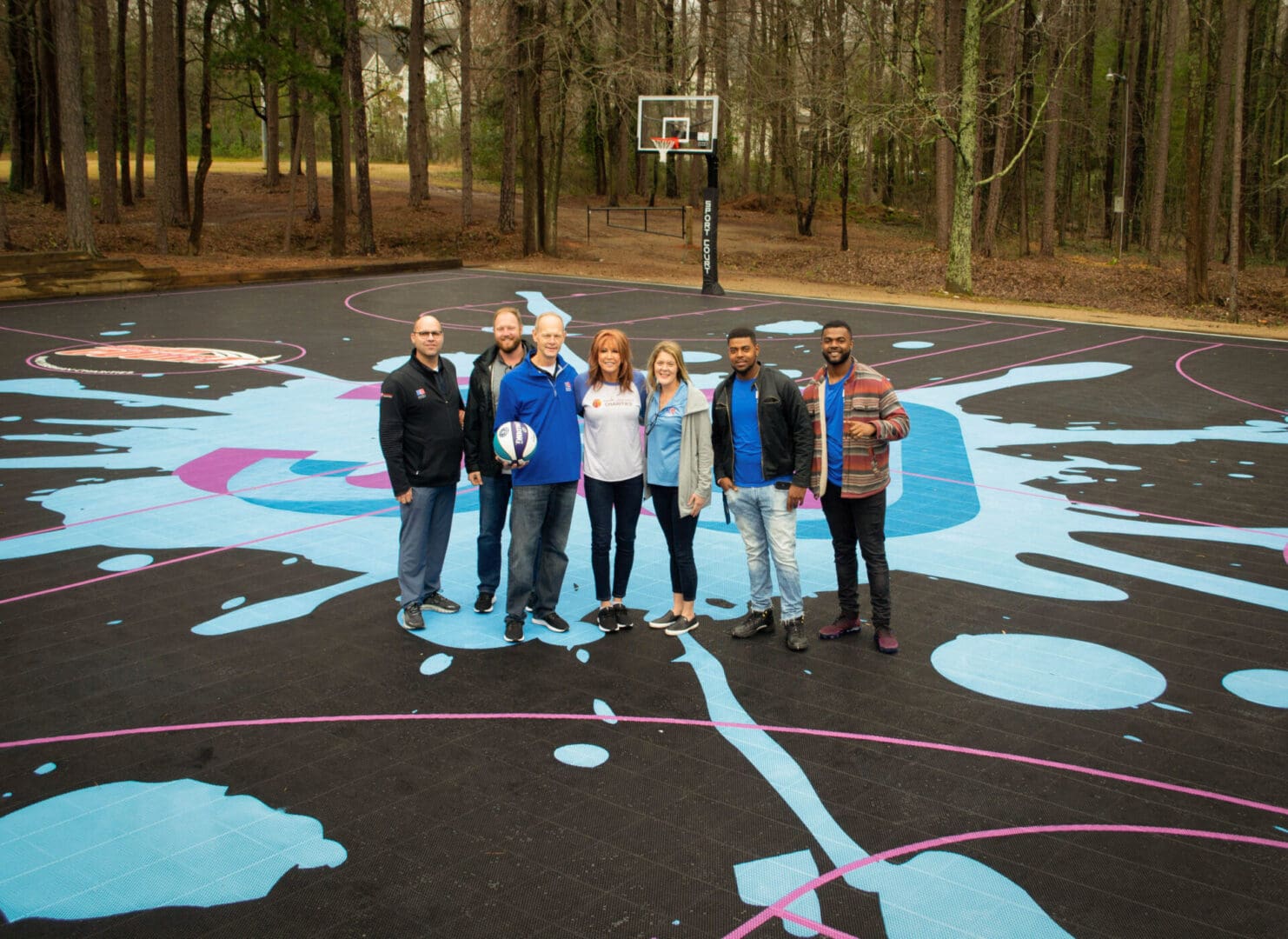 A group of people standing on top of a basketball court.