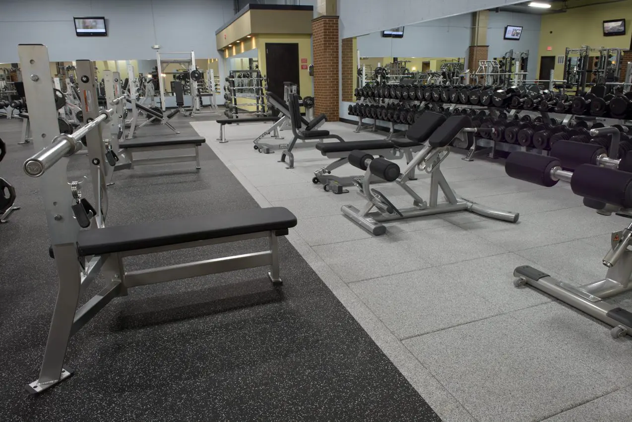 A gym with many benches and some weight machines