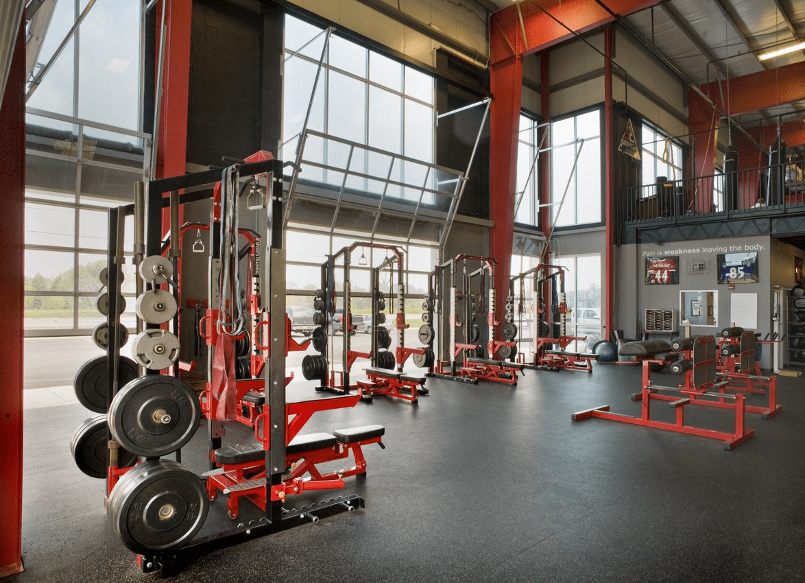 A gym with many machines and large windows.