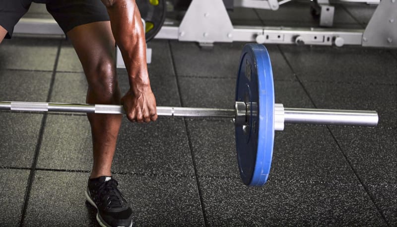 A man is lifting a barbell in the gym.