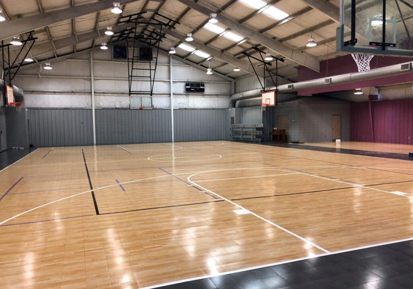 A basketball court with wooden floors and a large wall.