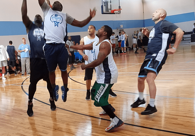 A group of men playing basketball on an indoor court.